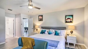 A bedroom with a bed, two bedside tables with lamps, a ceiling fan, and two wall-mounted pictures. - Bright Sebastian Home w/ Pool ~ 7 Mi to Beach! (Sebastian)