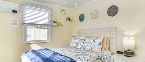 Un dormitorio con cama, mesita de noche, lámpara y elementos decorativos en la pared.