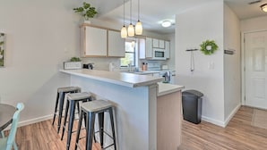 A modern kitchen with a bar area, wooden flooring, and a welcome sign. - Branson Vacation Rental w/ Resort Amenities (Branson)