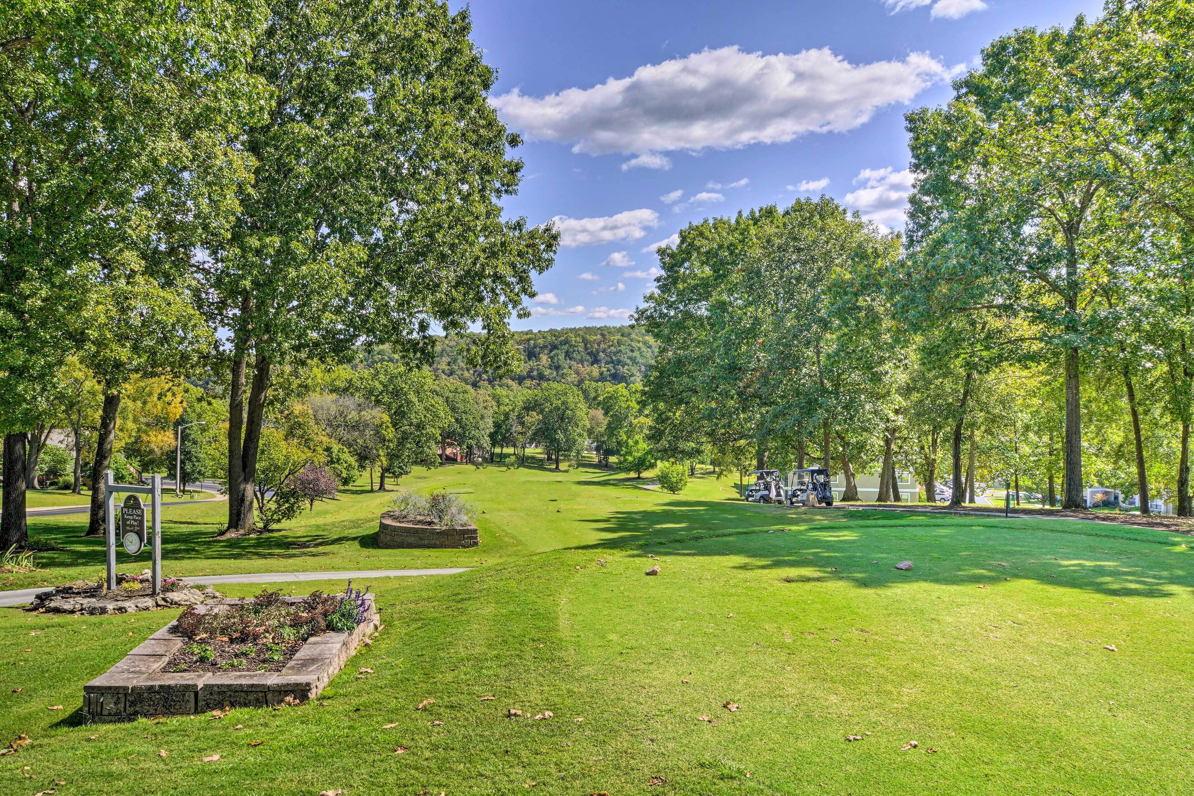 A well-maintained park with a grassy area, trees, and a stone monument.