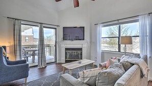 A living room with a fireplace, a television, a ceiling fan, and a view of the outside. - Branson Vacation Rental w/ Resort Amenities (Branson)