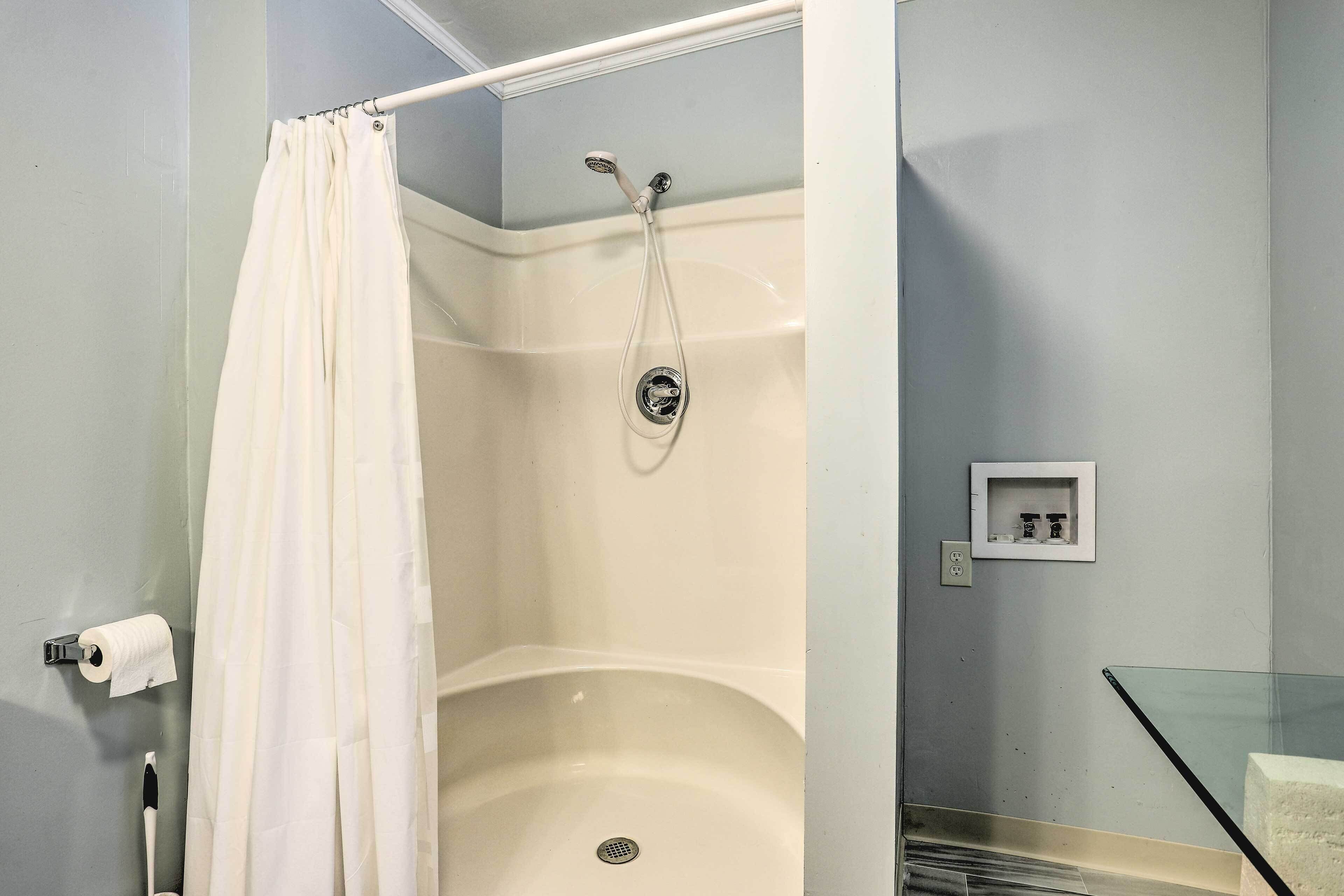 A bathroom with a shower, a toilet paper holder, and a glass shower door.