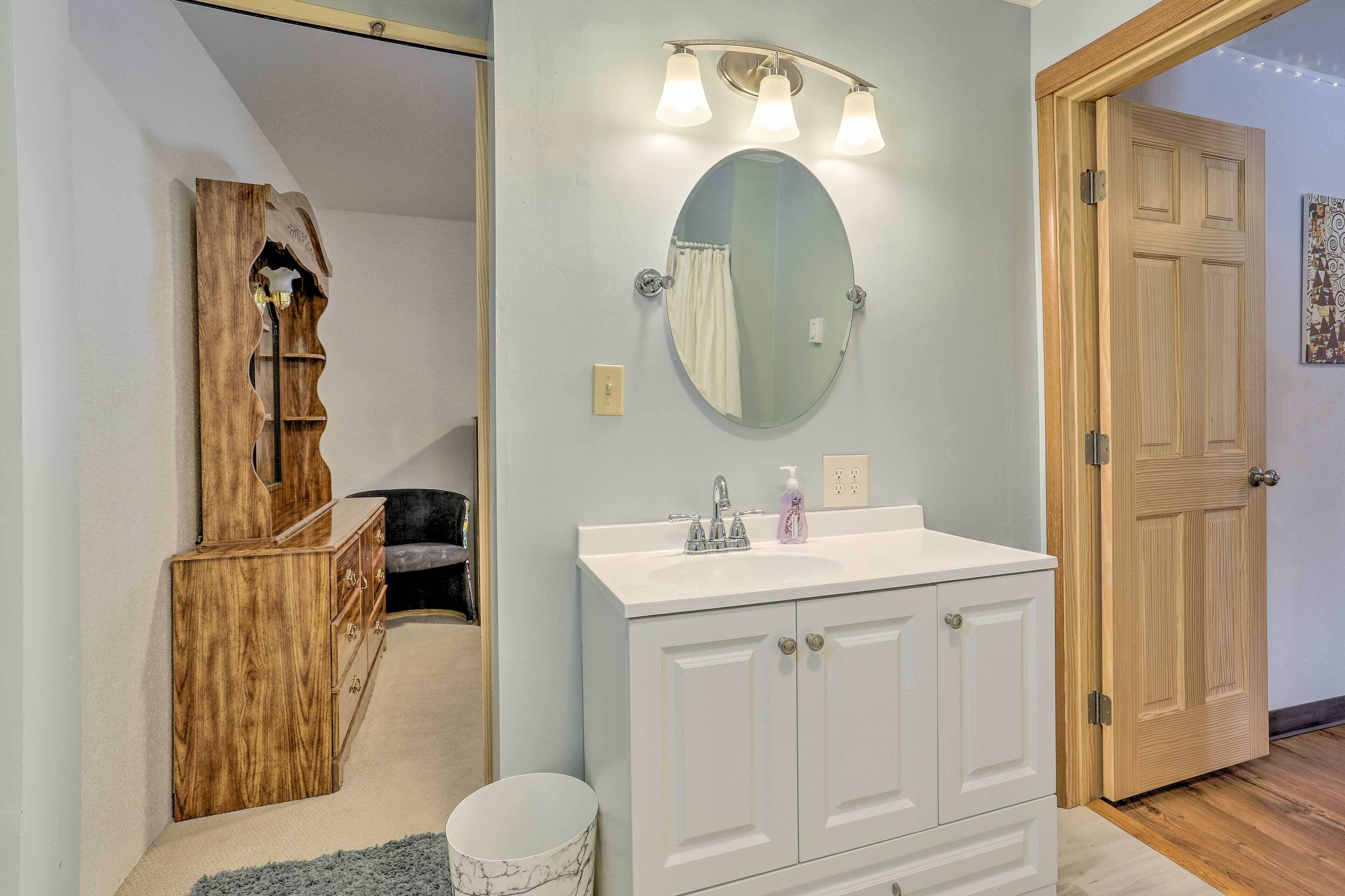 A bathroom with a white vanity, a round mirror, and a light fixture above the sink.