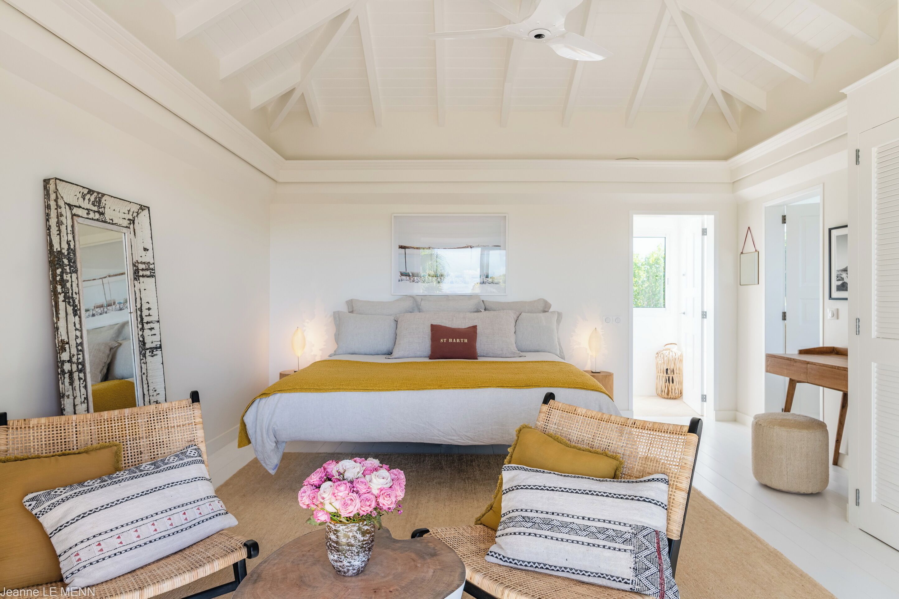 A bedroom with a bed, a large mirror, a window, and a view of the outdoors.