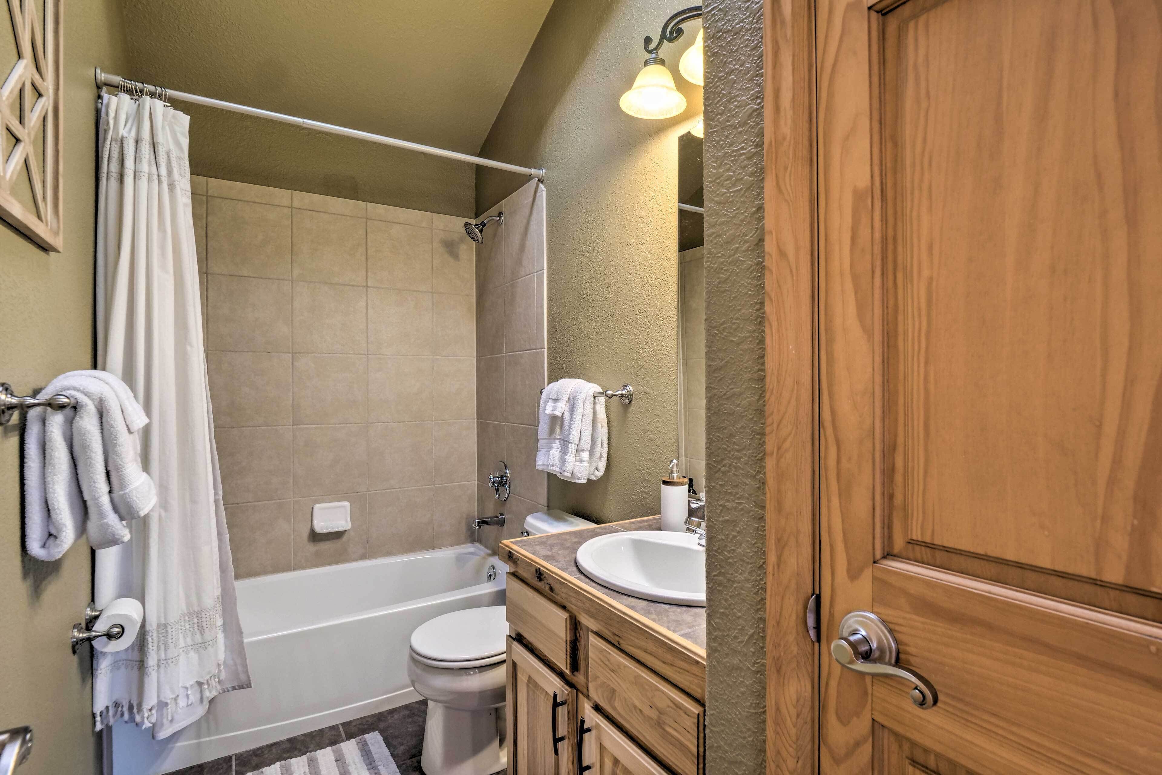 A bathroom with a bathtub, toilet, and sink, wooden cabinets, and a towel rack.