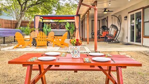 A patio with a wooden table set for dining, outdoor chairs, and a covered seating area with a ceiling fan. - San Antonio Home w/ Hot Tub & Arcade Games! (San Antonio)