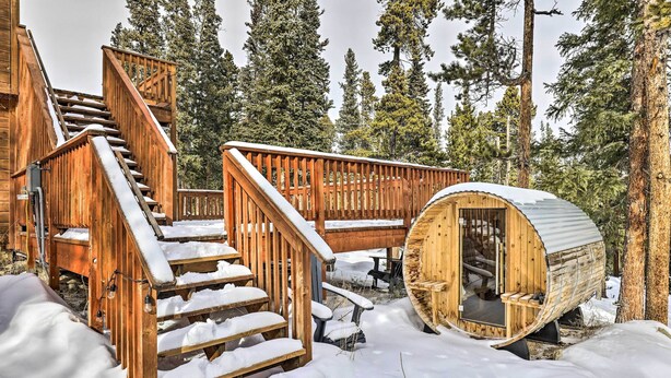 Une cabane en bois avec un escalier en colimaçon, une terrasse en bois et une pièce aménagée dans le style d’une cabane en rondins.