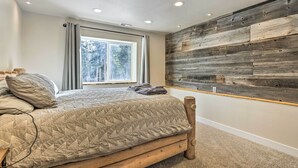 Une chambre avec un lit en bois, une grande fenêtre et un panneau mural en bois.