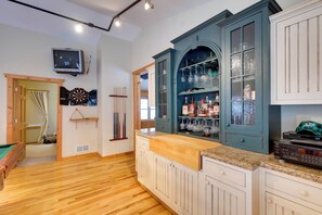 Een keuken met houten vloeren, een bar met een counter, kastjes en een televisie aan de muur.