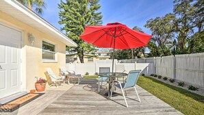 A backyard patio with a wooden deck, a red umbrella, and outdoor furniture.