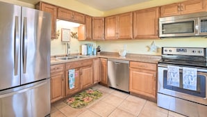 A kitchen with wooden cabinets, stainless steel appliances, and a tiled floor.