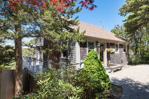 A two-story house with a covered porch, a wooden deck, and a well-maintained garden. - Peaceful Nauset Beach Sanctuary (Orleans)