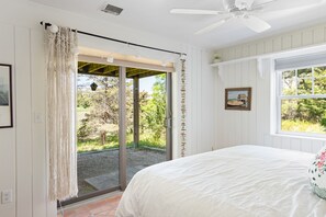 A bedroom with a bed, a window, a ceiling fan, and a view of the outdoors. - Peaceful Nauset Beach Sanctuary (Orleans)