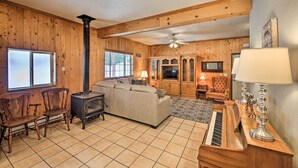 A cozy living room with a fireplace, sofa, chairs, a piano, and a television. - Family-friendly Sagle Vacation Rental w/ Deck (Sagle)