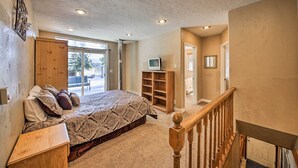 A bedroom with a bed, a wooden nightstand, a TV, and a built-in bookshelf. - Family-friendly Sagle Vacation Rental w/ Deck (Sagle)