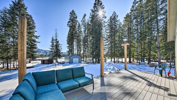 A wooden deck with a blue sofa, surrounded by tall trees and a snow-covered landscape. - Family-friendly Sagle Vacation Rental w/ Deck (Sagle)