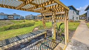 A wooden pergola structure with a garden area in front of a residential building. - 'sea-king Sol' Ocean-view Condo in Port Aransas! (Port Aransas)