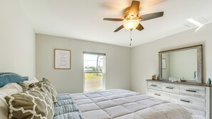 A bedroom with a bed, a ceiling fan, a dresser, and a window.