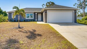 A two-story house with a garage, a small lawn, and a palm tree.