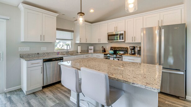 A modern kitchen with white cabinetry, stainless steel appliances, and a granite countertop.