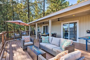 A covered outdoor deck with wicker furniture, a fire feature, and a table.
