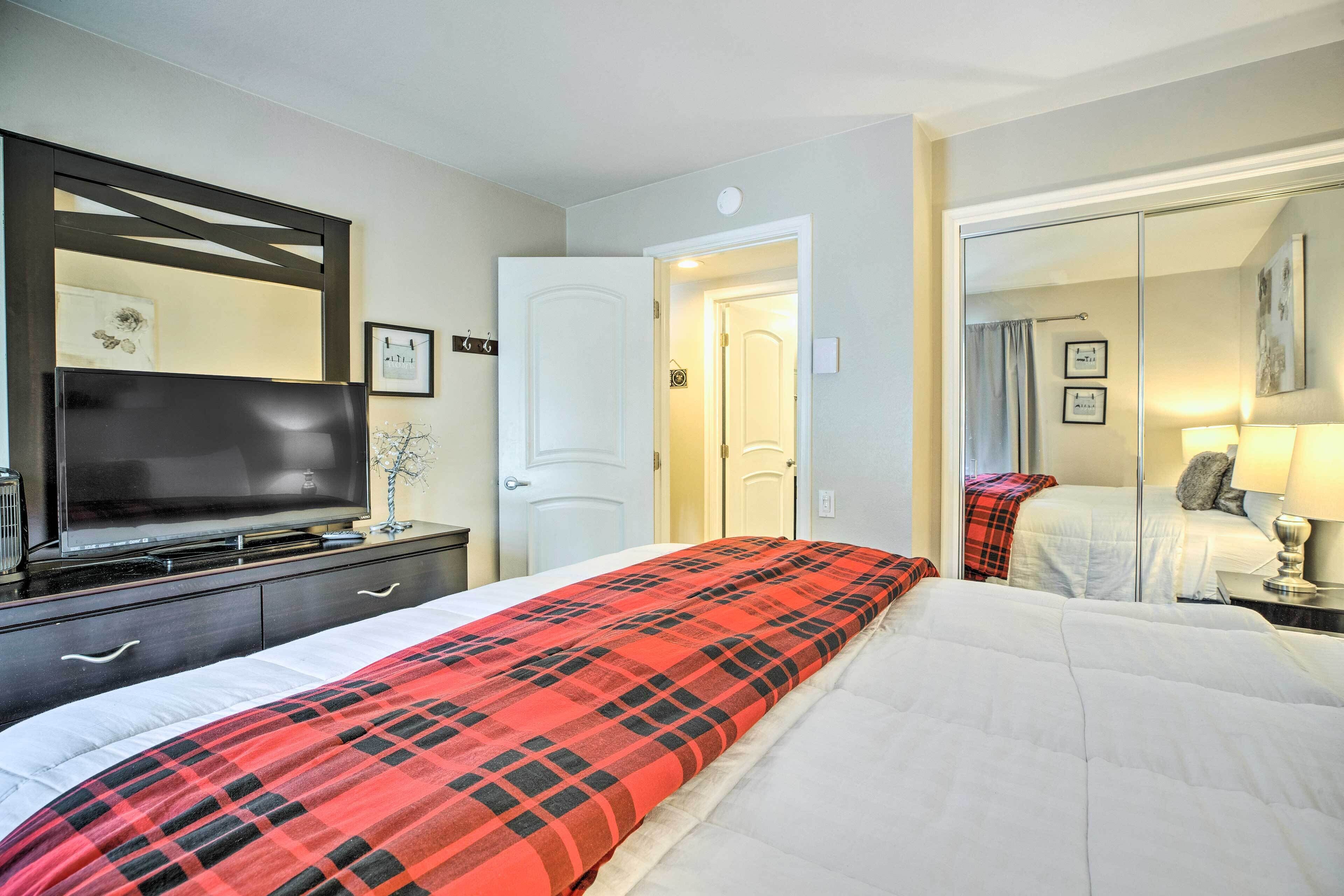 Una habitación de hotel con cama, televisión, cómoda y espejo.