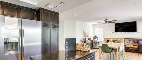 A modern kitchen with dark wooden cabinets, stainless steel appliances, and a black granite countertop.