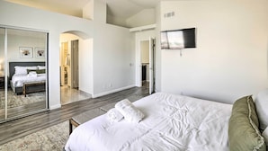 Un dormitorio moderno con una cama grande, ventilador de techo, televisor de pantalla plana y vestidor.