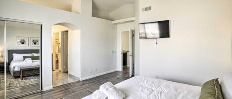 Un dormitorio moderno con una cama grande, ventilador de techo, televisor de pantalla plana y vestidor.