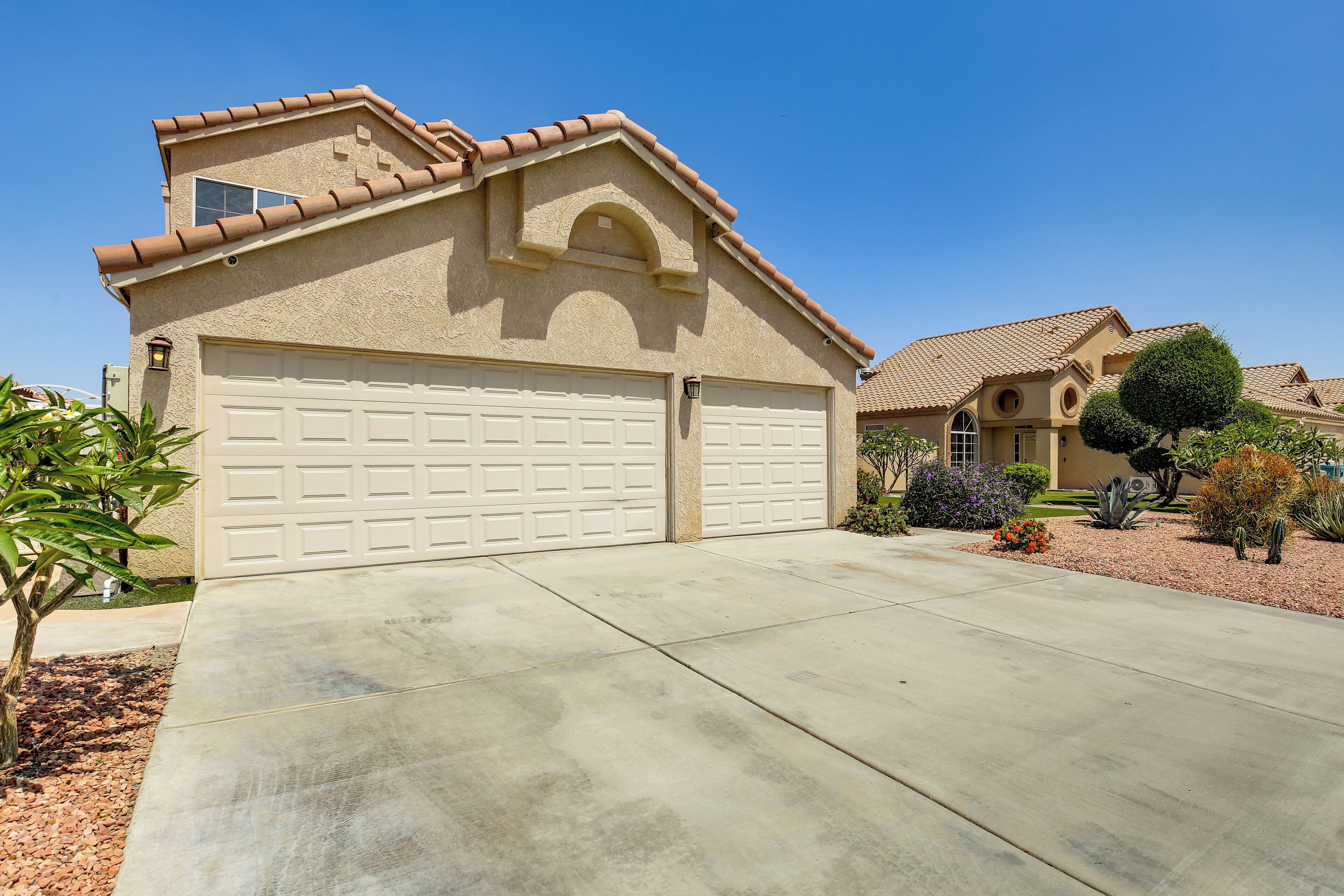 A residential house with a beige facade, a large garage, and a well-maintained driveway.