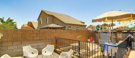 A patio area with white wicker chairs, a fire pit, and a wooden table.