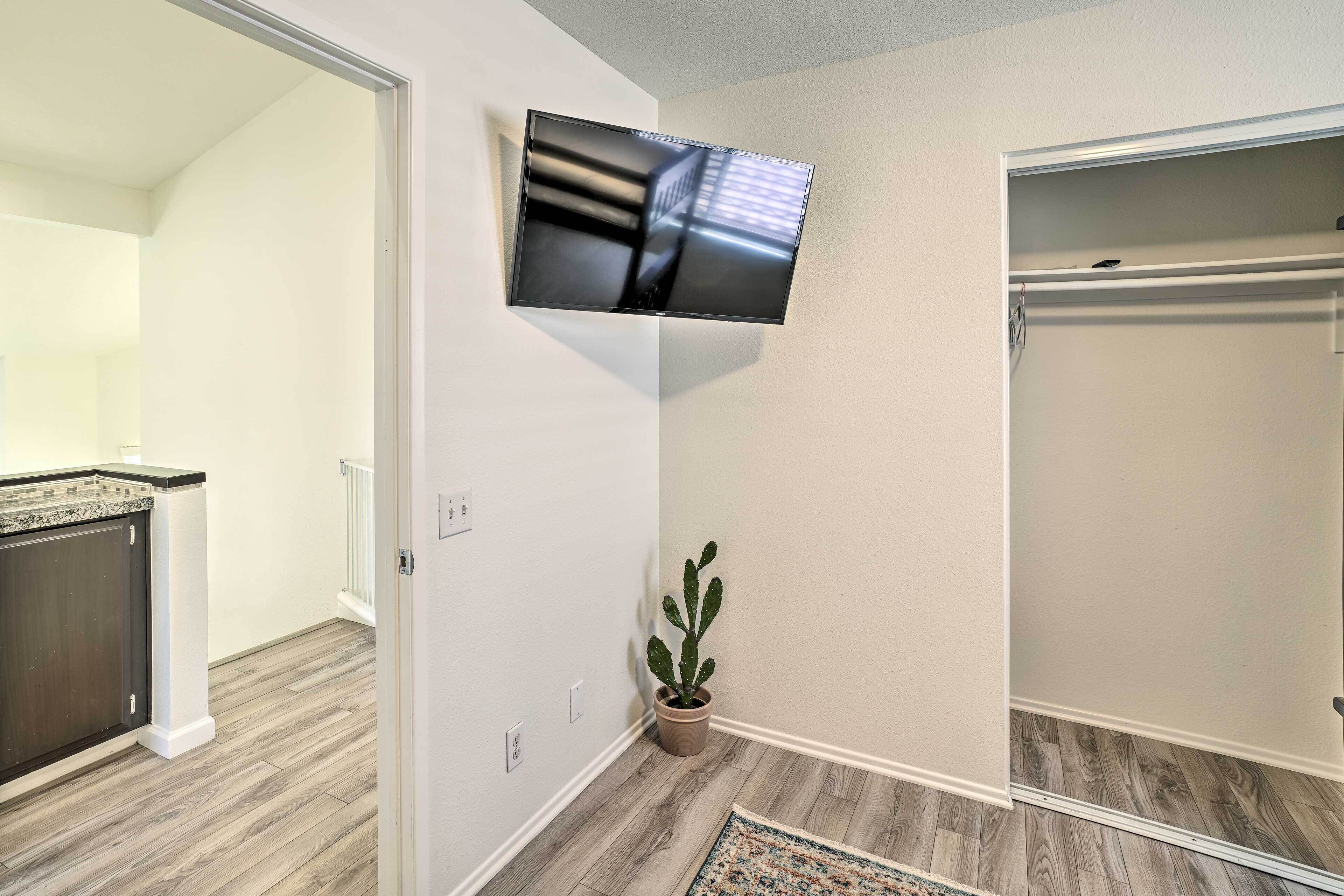 Une chambre moderne avec un téléviseur à écran plat fixé au mur, un cactus en pot et un plancher en bois.