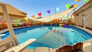 Una piscina con banderas triangulares de colores, una silla de piscina y una escalera.
