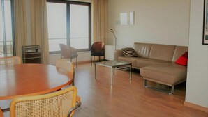 Una sala de estar moderna con una mesa de comedor de madera, dos sofás, una mesa auxiliar y un ventanal con cortinas.