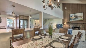 A dining area with a wooden table set for four, surrounded by chairs, a chandelier, and a fireplace. - Pagosa Springs Condo Near Springs + Trails! (Pagosa Springs)