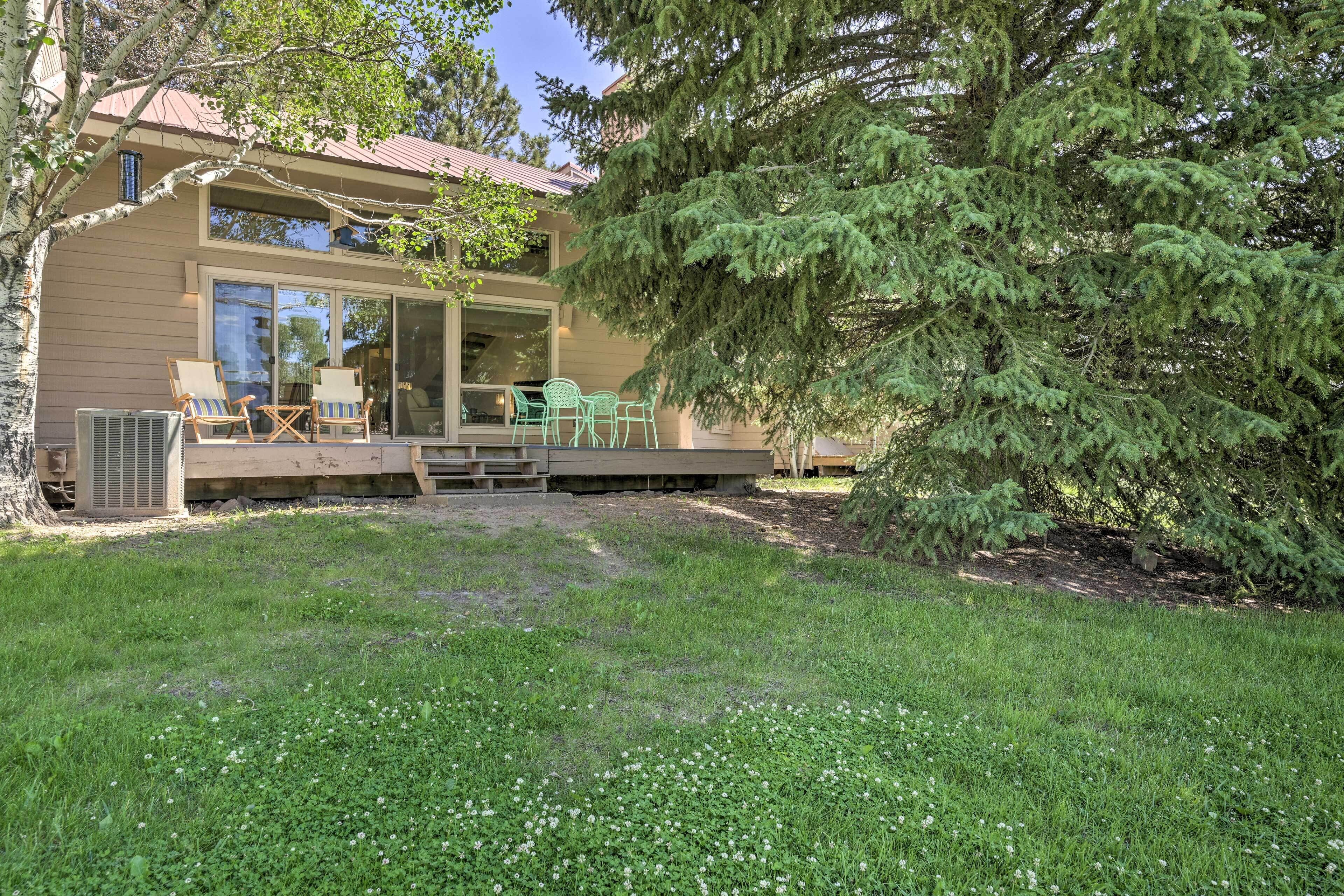 Une maison moderne dotée d’un patio couvert, d’un espace salon extérieur et d’un grand arbre.