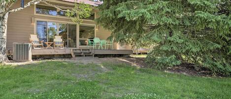 Une maison moderne dotée d’un patio couvert, d’un espace salon extérieur et d’un grand arbre.