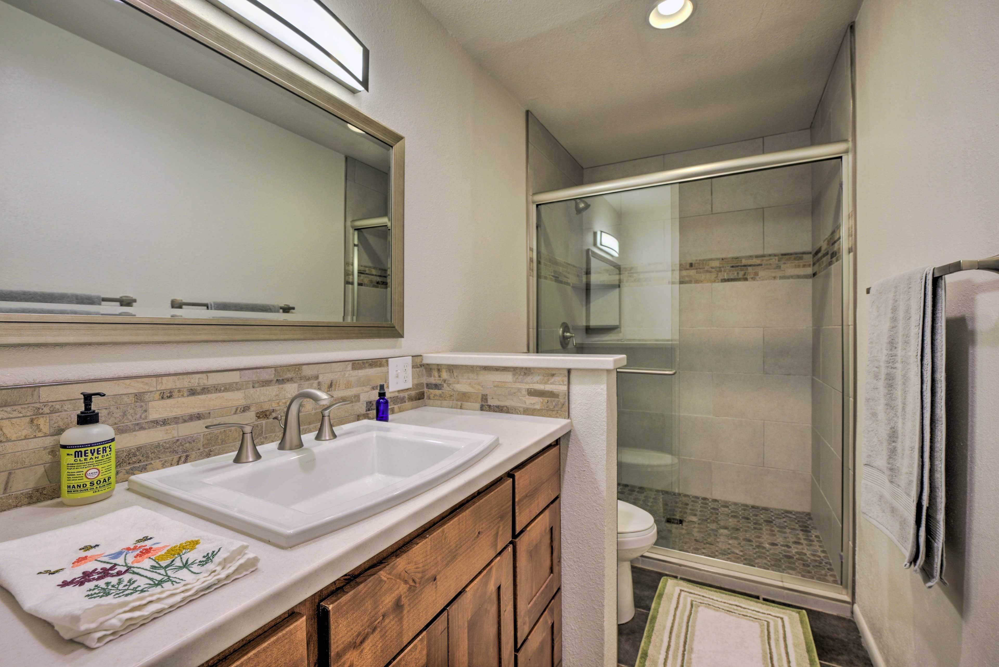 A bathroom with a double sink, a mirror, a shower enclosure, and a towel rack.