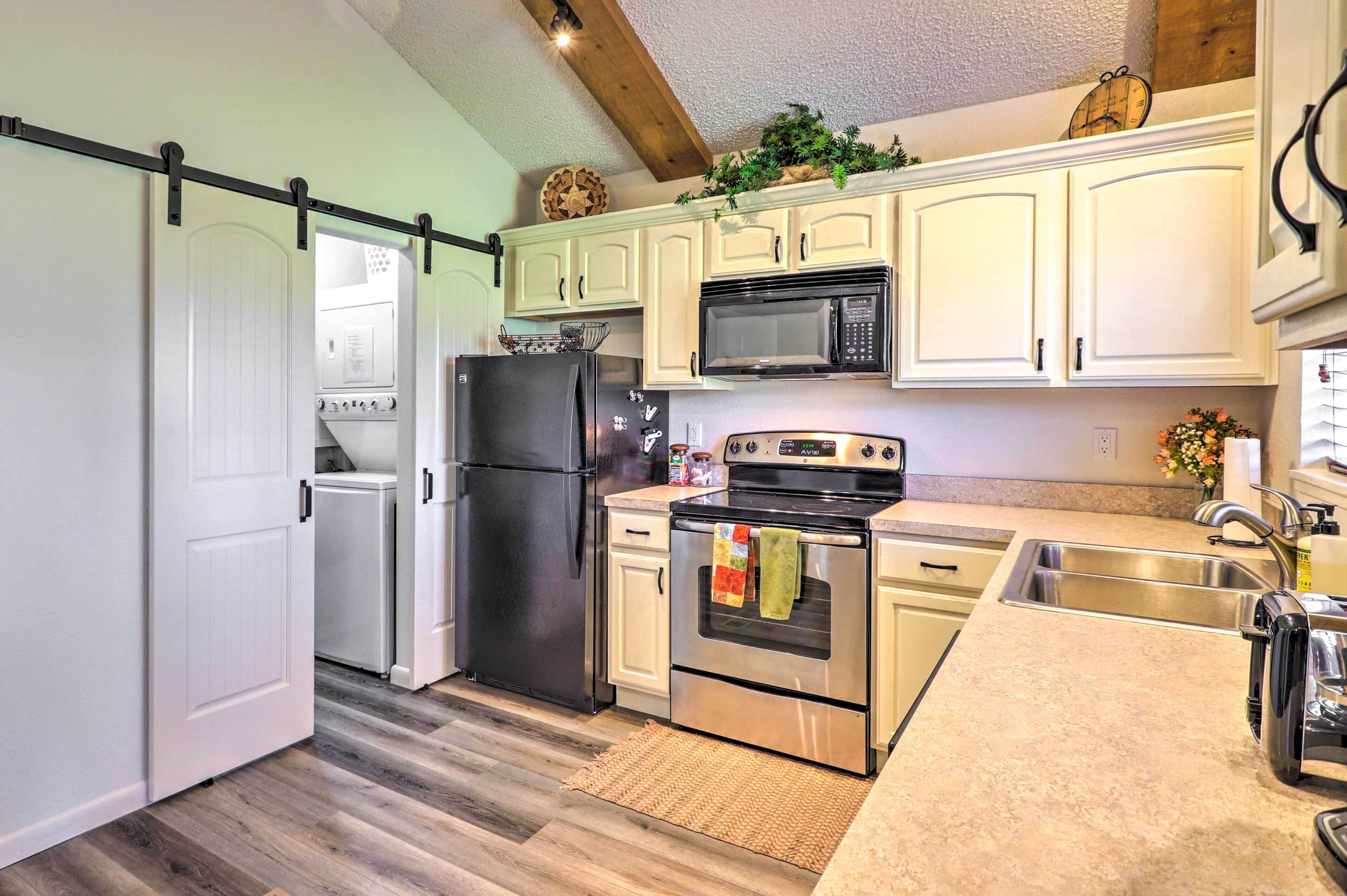 A kitchen with white cabinets, a black refrigerator, a stainless steel oven, and a microwave.