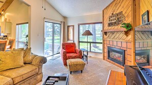 A cozy living room with a fireplace, a red armchair, and a patterned sofa. - Cozy Pagosa Springs Townhome w/ Patio! (Pagosa Springs)