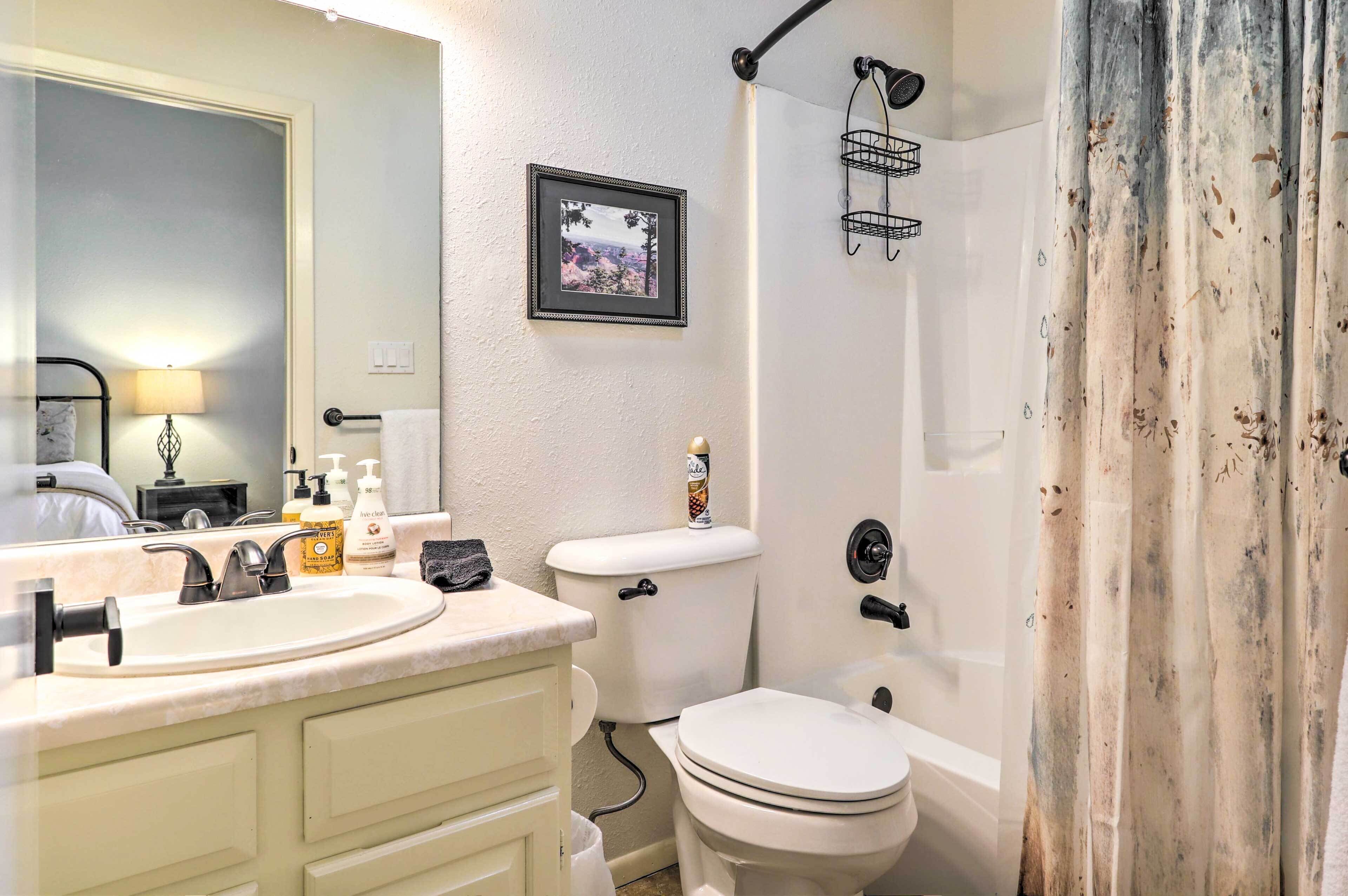 Une salle de bain avec un lavabo, des toilettes et une baignoire. Un tableau encadré est accroché au mur, et il y a un porte-serviettes.