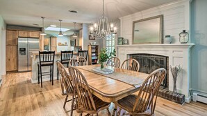 A spacious kitchen with wooden cabinets, a stainless steel refrigerator, a dining table with chairs, and a chandelier. - Clemson Getaway < 3 Mi to Memorial Stadium! (Clemson)