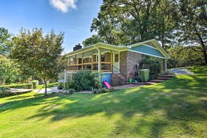 A two-story house with a covered porch, brick exterior, and a small front yard with a hammock and a slide.
