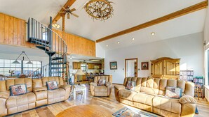 A spacious living room with leather sofas, a wooden coffee table, and a spiral staircase. - New Mexico Cabin Hideaway w/ Eagle Nest Lake Views (Eagle Nest)
