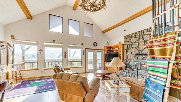 A spacious living room with a large window, a fireplace, and a cozy seating area. - New Mexico Cabin Hideaway w/ Eagle Nest Lake Views (Eagle Nest)