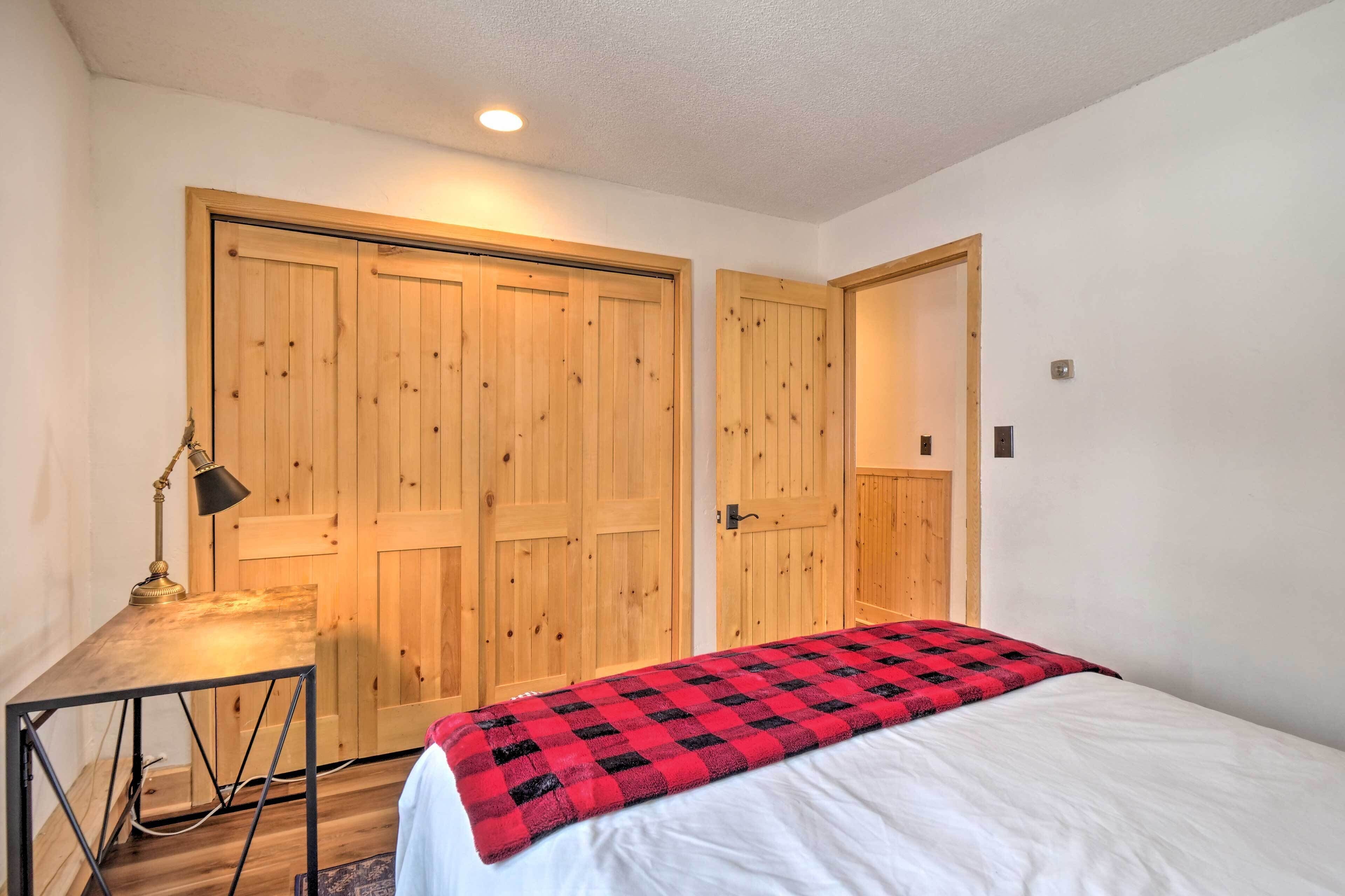 A bedroom with a bed, a desk, and two wooden doors.