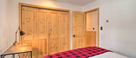 A bedroom with a bed, a desk, and two wooden doors.