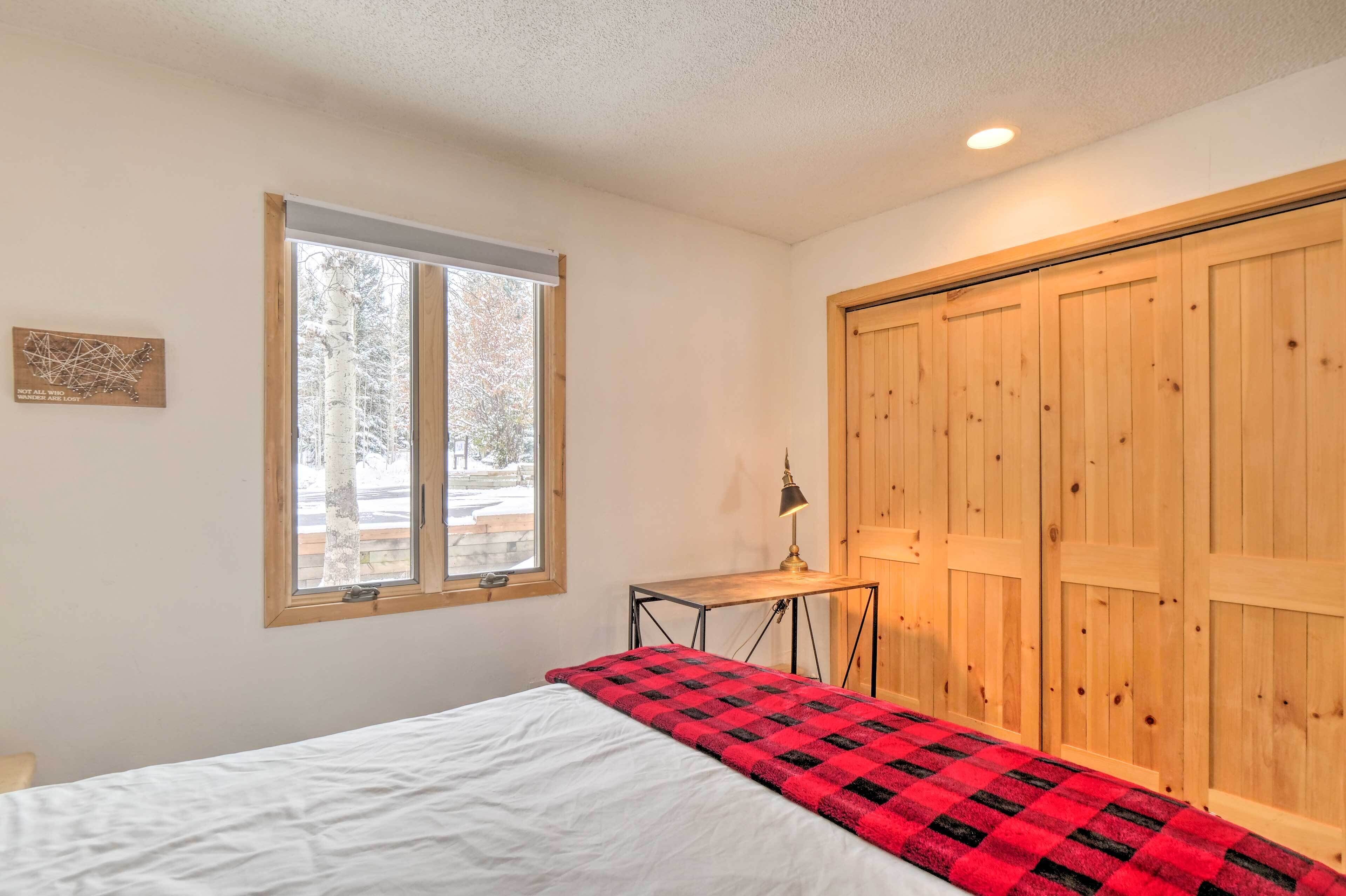 A bedroom with a bed, a window, a desk, and a wardrobe.