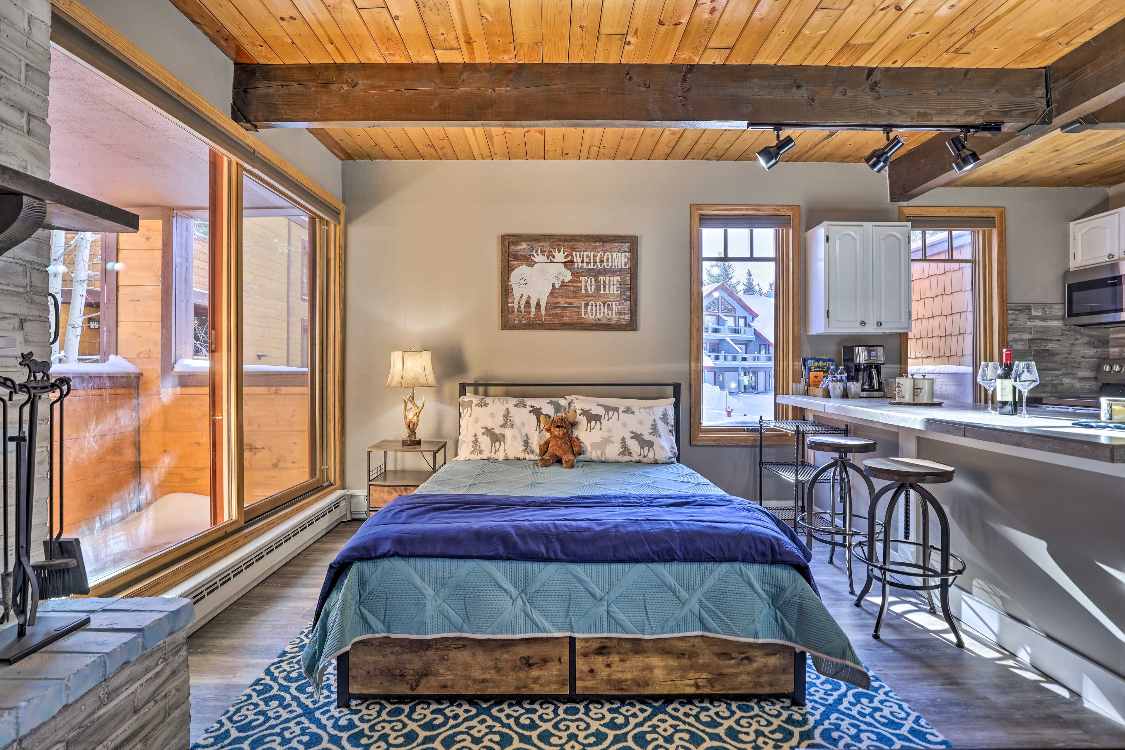 Ein gemütliches Schlafzimmer in einer Lodge mit einem großen Bett, einer Holzbank, einem Nachttisch und einer Bar mit Hockern.
