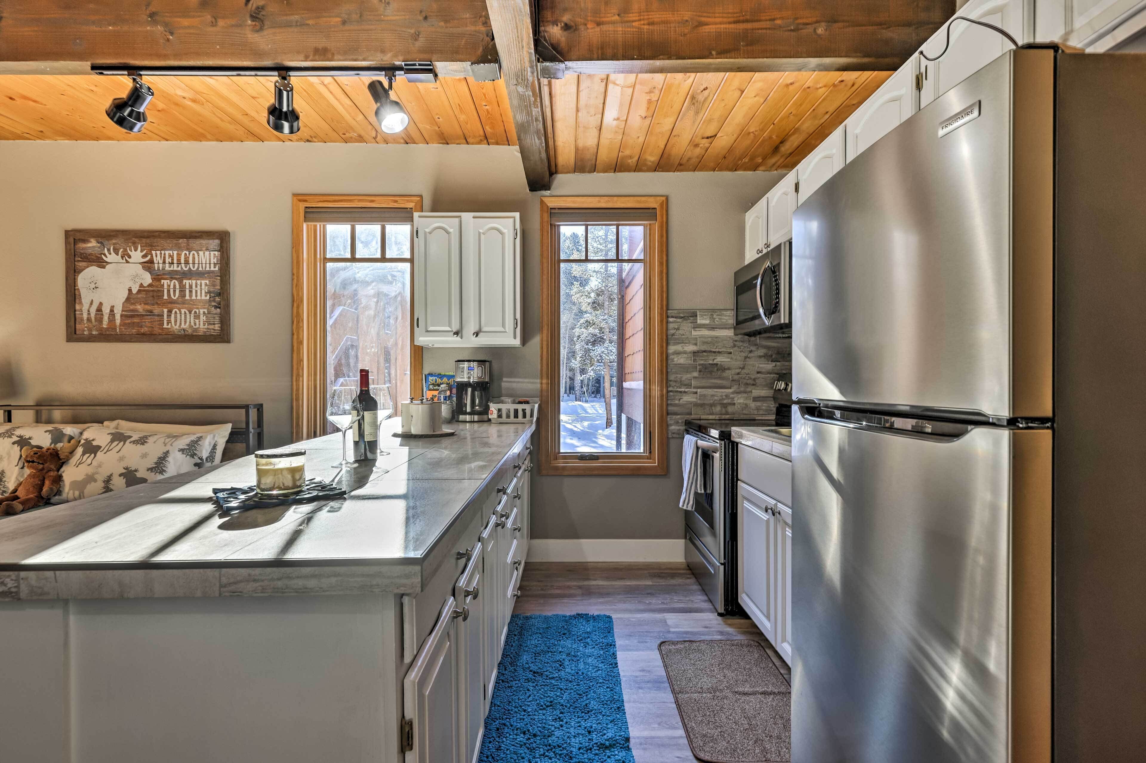 A modern kitchen with a stainless steel refrigerator, white cabinets, and a blue rug.